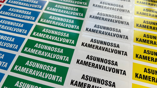 ASUNNOSSA KAMERAVALVONTA-tarra